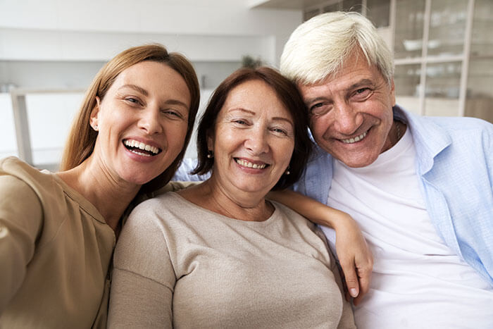 mature man and woman smiling with adult daughter