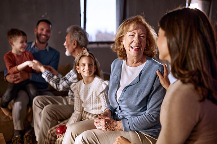 senior woman smiling at home surrounded by family